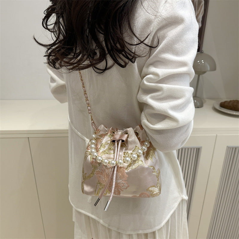 Person wearing a white outfit with a decorative pink handbag.