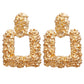 Gold textured earrings on a white background
