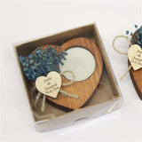 Heart-shaped wooden coaster with dried flowers and a candle, tied with twine and a heart-shaped tag, in a box.