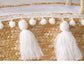 Woven basket with white tassels and pom-poms on a white background