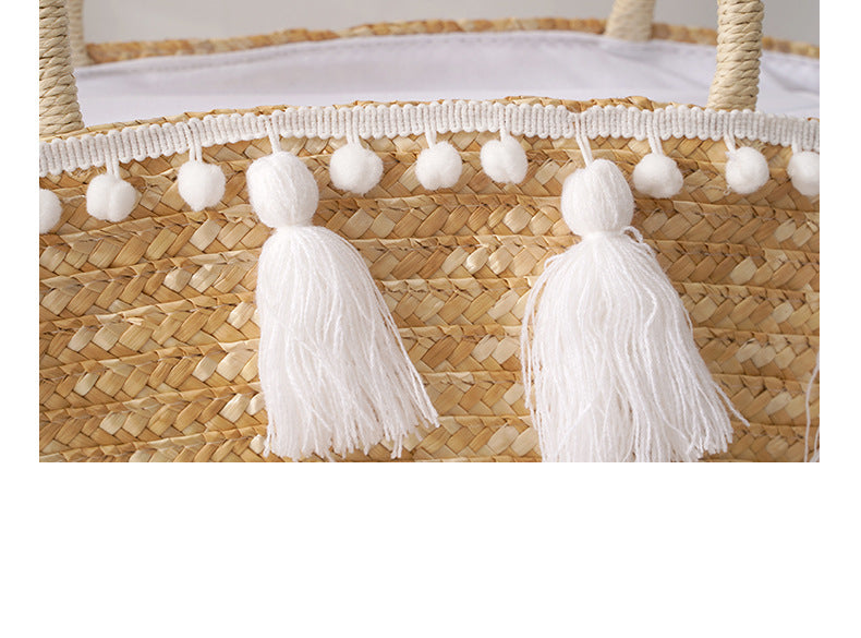 Woven basket with white tassels and pom-poms on a white background