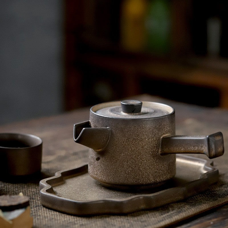 Traditional ceramic teapot and cup on a wooden tray with a blurred background