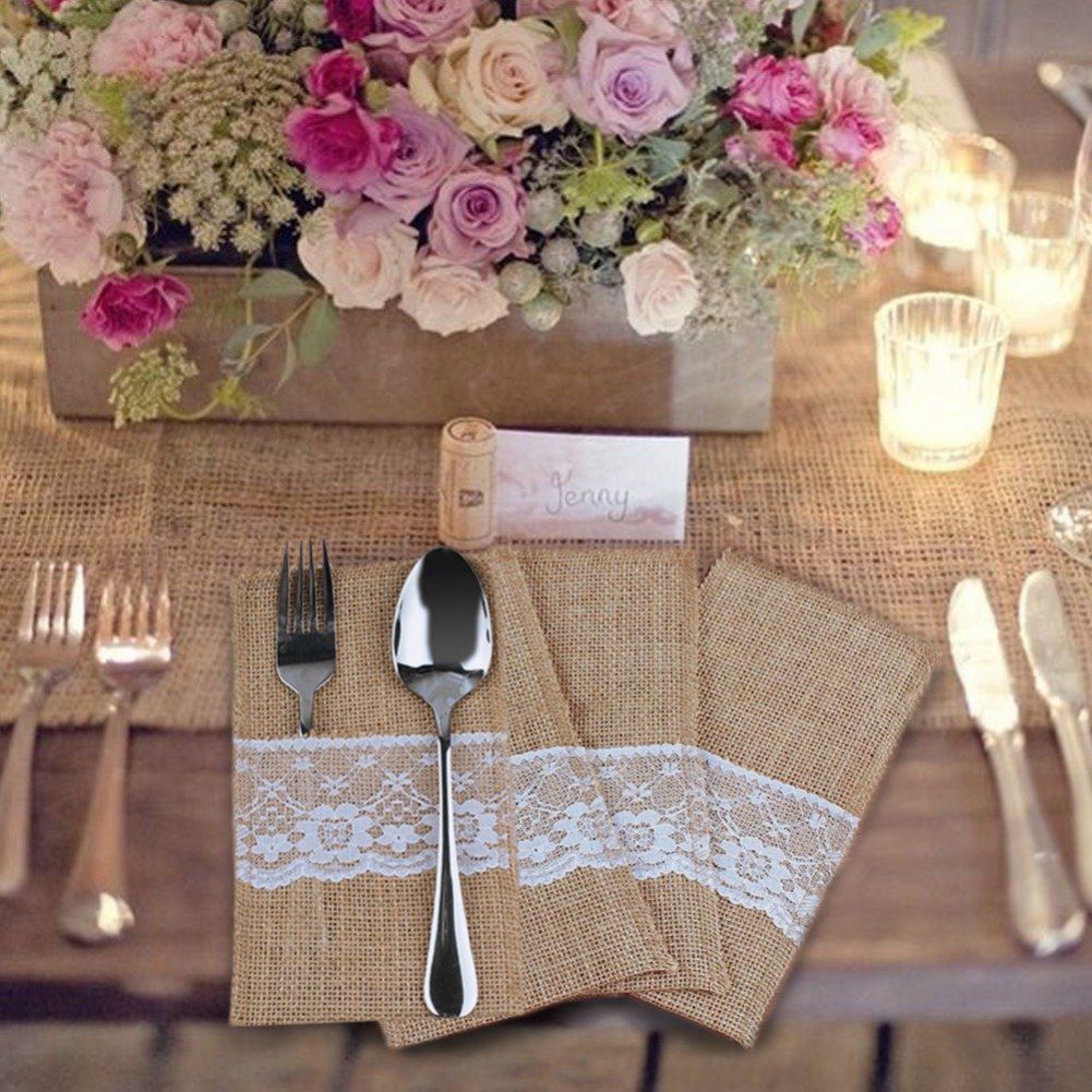 Table setting with floral centerpiece, lace napkin, and cutlery on a wooden table.