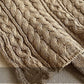 Close-up of a textured beige knitted blanket on a soft gray background