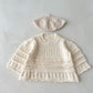 Knitted baby sweater and hat set on a light gray background