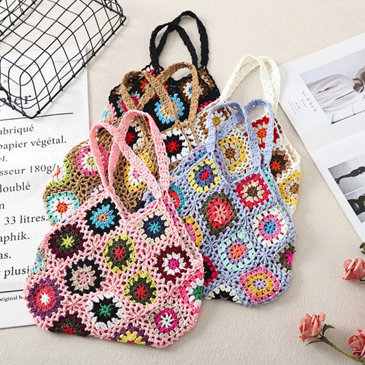 Three colorful crocheted bags on a surface with a magazine and flower in the background.