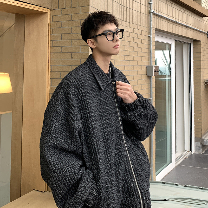 Person wearing a dark coat standing outside a building with a glass door.