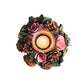 Decorative candle holder with flowers and pinecones on a white background