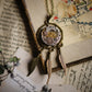 Vintage-style necklace with mechanical heart pendant and feathers on an old book background