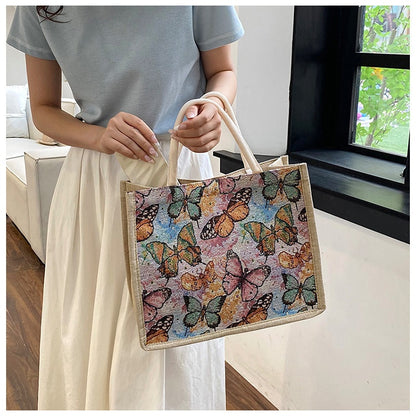 Person holding a tote bag with butterfly design indoors