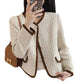 Beige tweed jacket with brown trim held by a person, with a brown handbag on a white background.