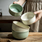 Person holding two ceramic bowls on a wooden surface
