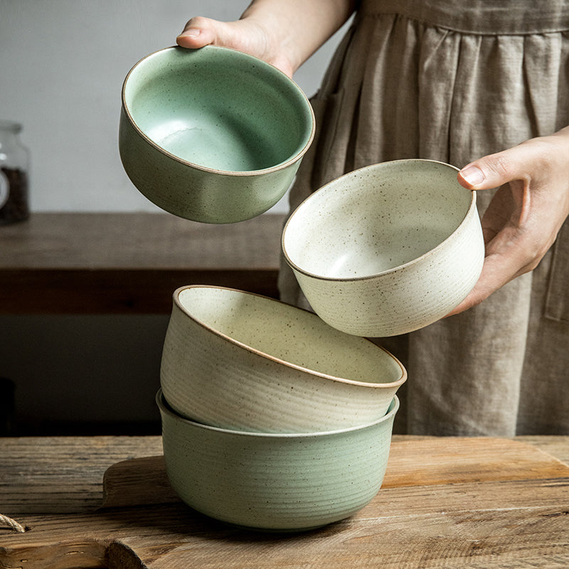 Person holding two ceramic bowls on a wooden surface