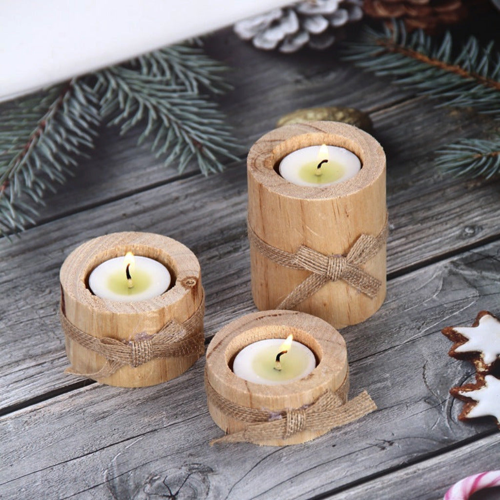 Three wooden candle holders with candles on a rustic wooden surface with decorative elements.