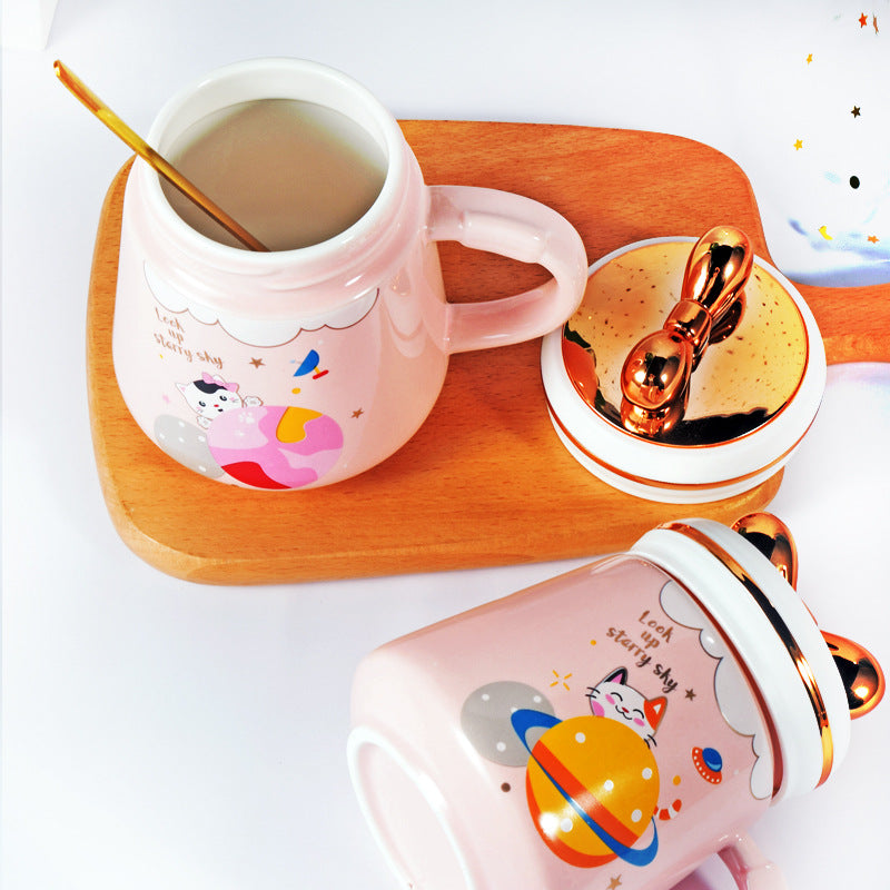 Two pink mugs with gold accents on a wooden tray
