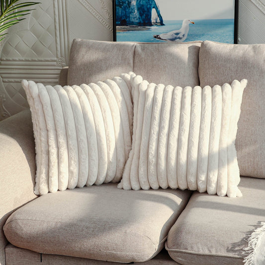 Gray sofa with white textured pillows and a decorative painting in the background.