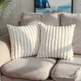 Gray sofa with white textured pillows and a decorative painting in the background.