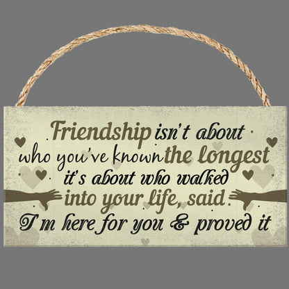 Wooden sign with a friendship quote on a gray background