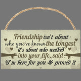 Wooden sign with a friendship quote on a gray background