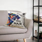 Decorative pillow with colorful dog illustration and text on a gray sofa.