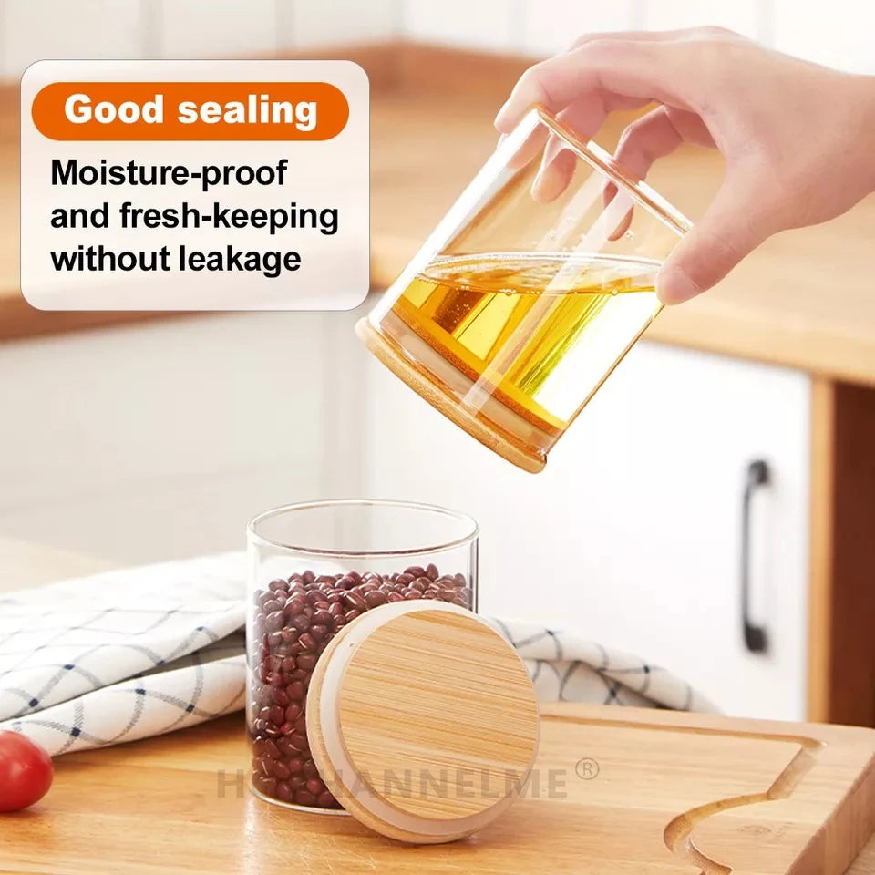 Glass jar with wooden lid being poured into another jar on a kitchen counter.