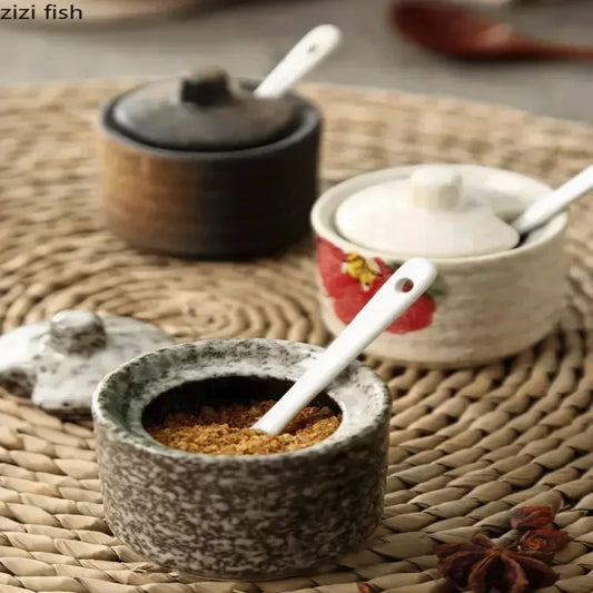 Decorative ceramic containers with lids and spoons on a woven mat