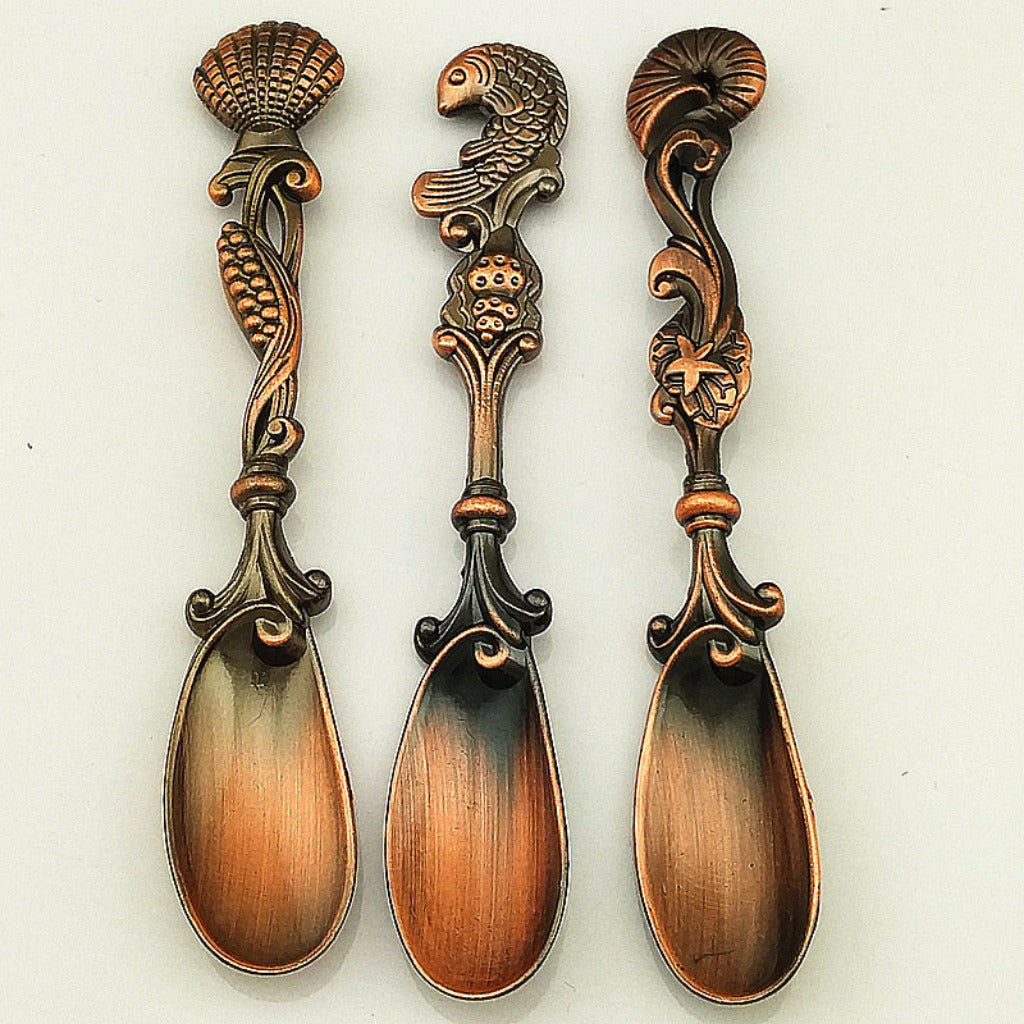 Three ornate spoons with decorative handles on a white background