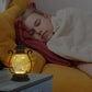 Person sleeping on a yellow pillow with a glowing lantern next to them