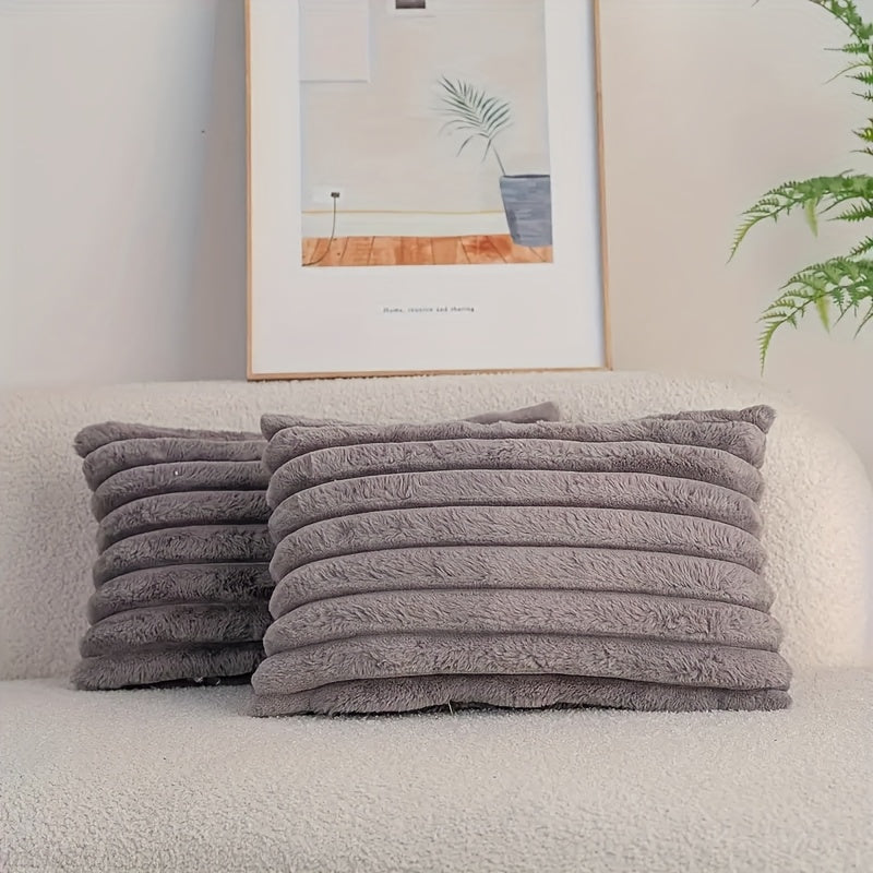 Stack of gray pillows on a sofa with a framed picture and plant in the background