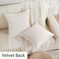 White textured pillows and blanket on a beige sofa with 'Velvet Back' label.