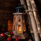 Wooden lantern with a candle inside, surrounded by natural elements like branches and berries.