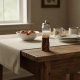 Wooden toothpick holder with toothpicks on a farmhouse table with saucers and cups and bowl of apples