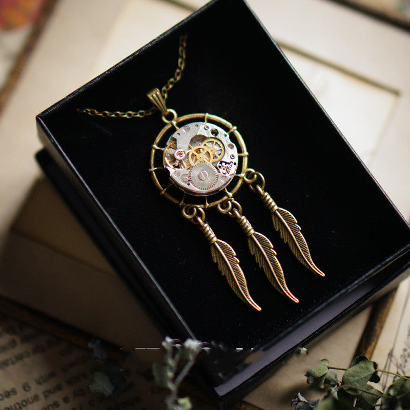 Steampunk-style necklace with gears and feathers on a black box