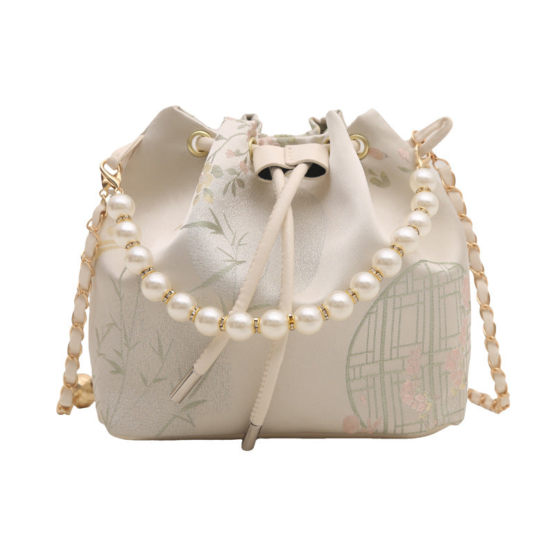 White drawstring bag with pearl detailing on a white background