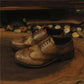 Pair of brown leather shoes on a wooden surface with a rustic background