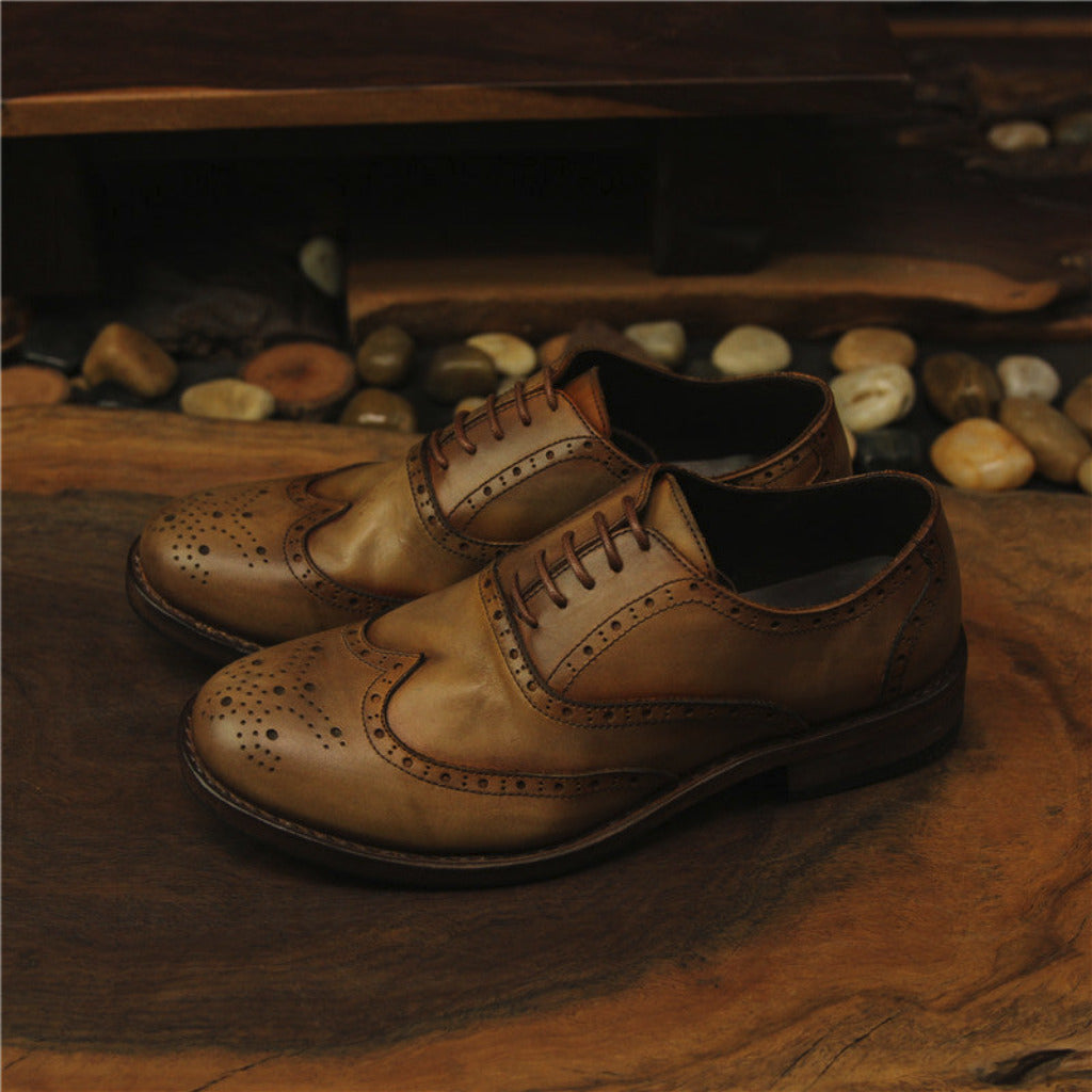 Pair of brown leather shoes on a wooden surface with a rustic background