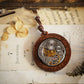 Vintage-style pocket watch pendant on a textured surface with floral elements