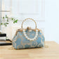 Blue floral handbag with pearl chain on a wooden surface