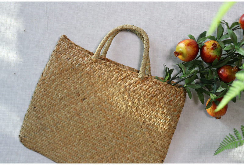 Woven straw bag on a light background with fruits and leaves.