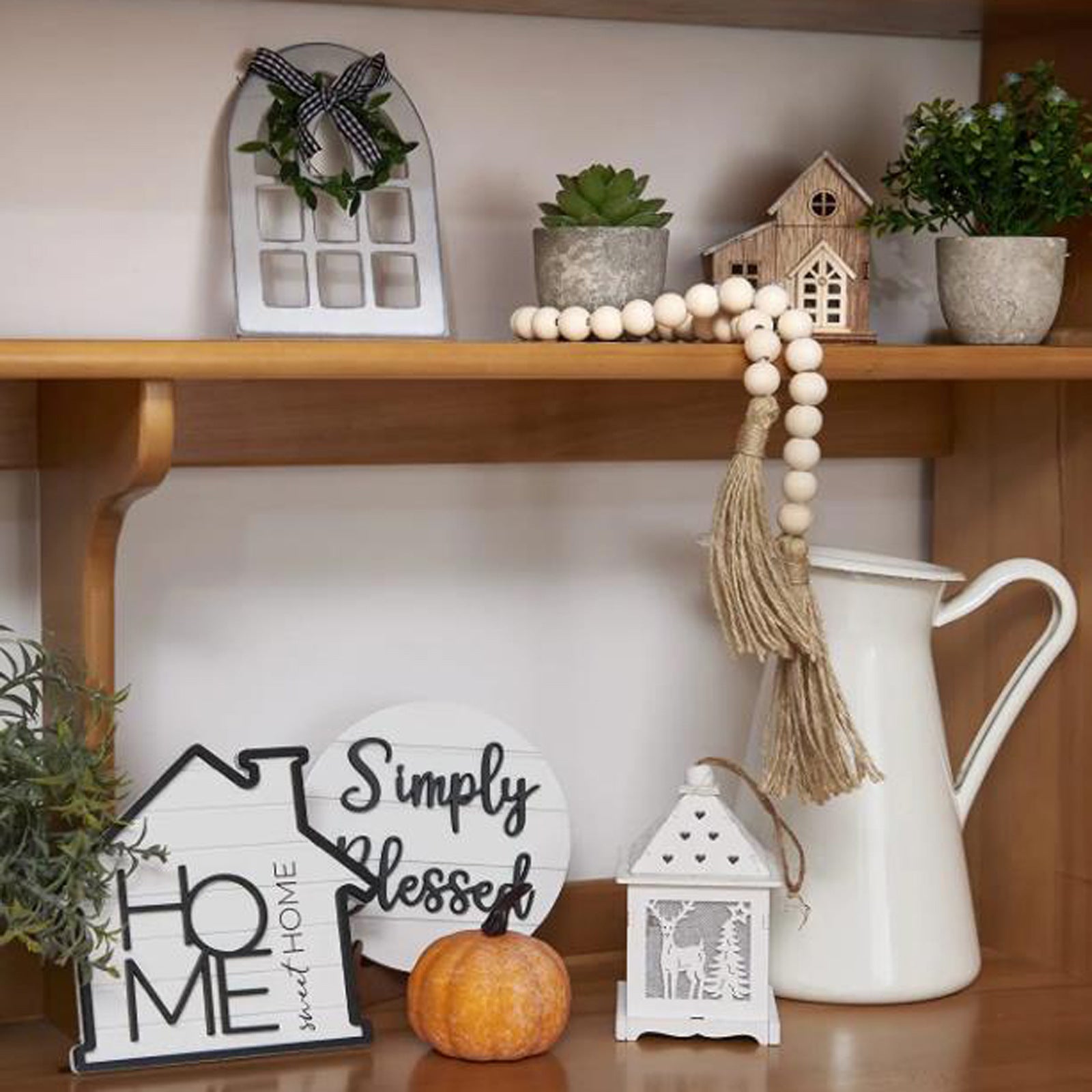 Decorative shelf with home decor items including a pitcher, pumpkins, and signs.