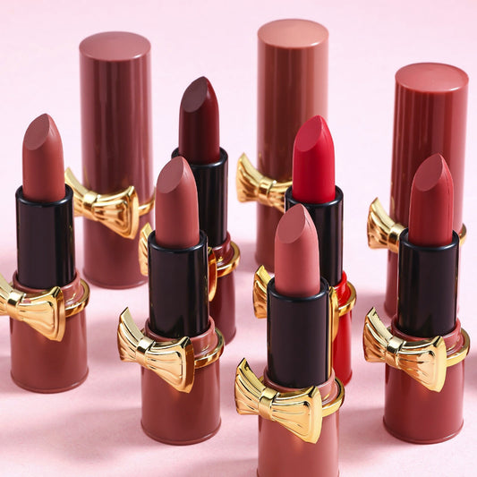 Set of lipsticks with gold and black accents on a pink background