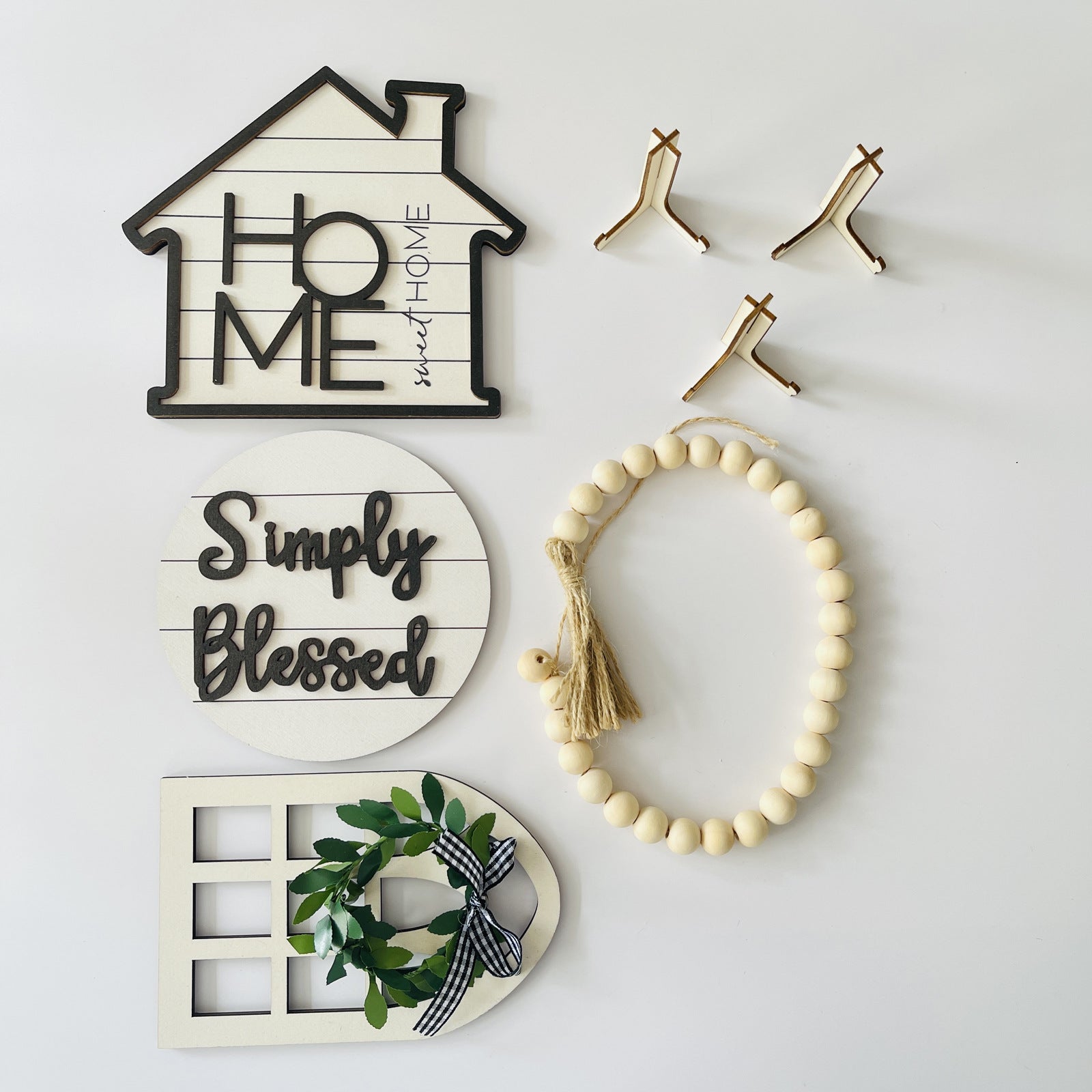 Decorative wall art pieces including a house-shaped sign, 'Simply Blessed' plaque, and a beaded wreath on a white background.