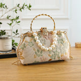 Decorative handbag with floral pattern and pearl embellishments on a wooden surface.