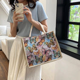 Person holding a phone and a tote bag with butterfly design indoors.