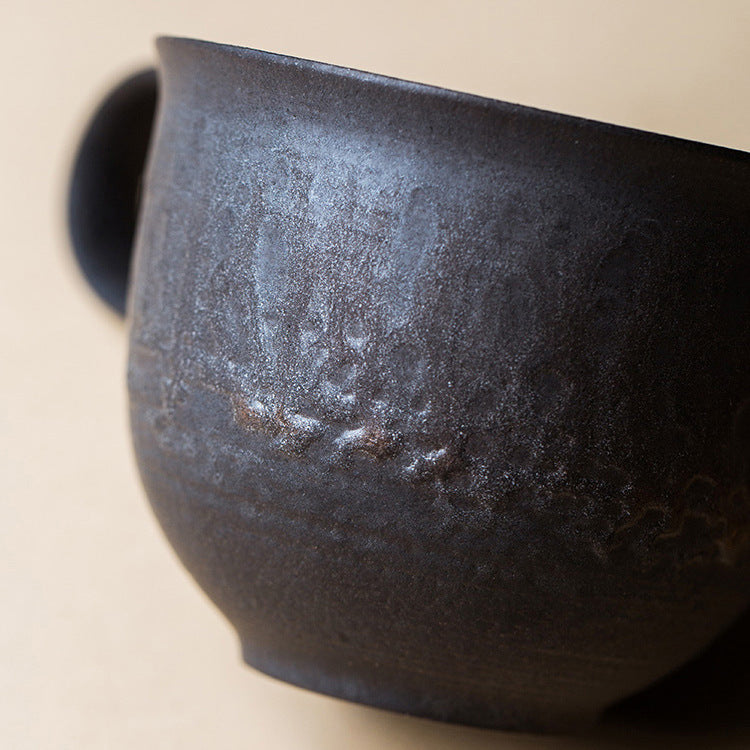 Close-up of a dark ceramic bowl with a textured surface on a beige background