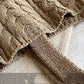 Close-up of a textured beige blanket on a neutral background