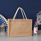 Brown jute bag with white handles on a gray surface against a blue wall.