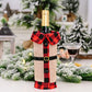 Wine bottle wrapped in a red and black checkered pattern with a plaid collar, set against a festive background.