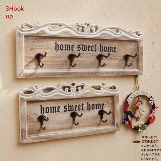 Wooden wall hooks with 'home sweet home' text on a beige background