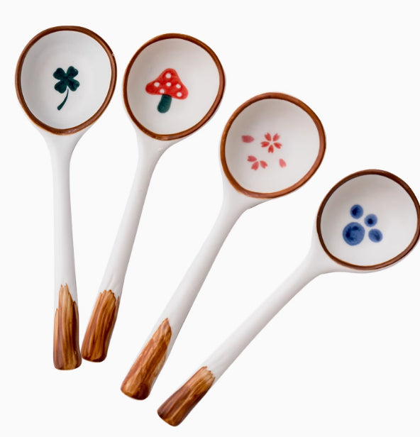 Set of four ceramic spoons with wooden handles and colorful designs on the bowls.